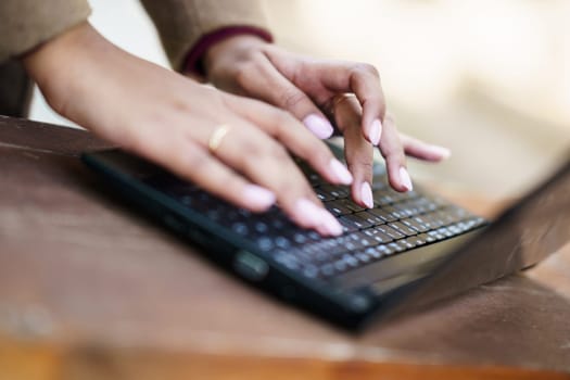 A closeup view of delicate and gentle hands gracefully typing on a sleek laptop, showcasing an enjoyable blend of creativity and productivity in a serene and peaceful setting that inspires work