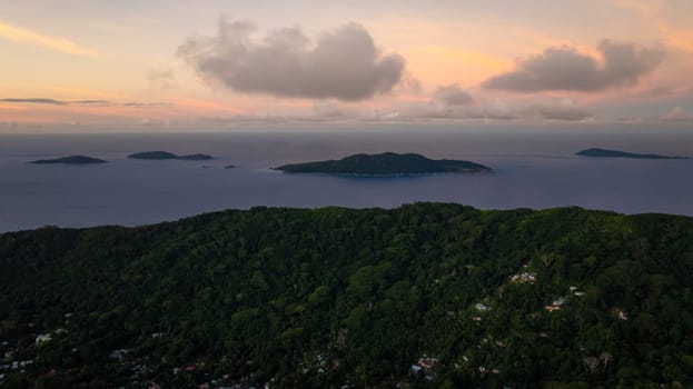 Distant islands seen under a colorful sunset sky over the ocean. Seychelles.