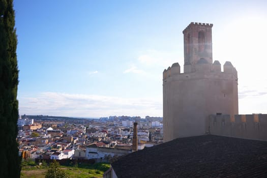 Ancient watchtower of the Badajoz fortress stands above the cityscape, with morning sunlight illuminating the skyline and the surrounding architecture.