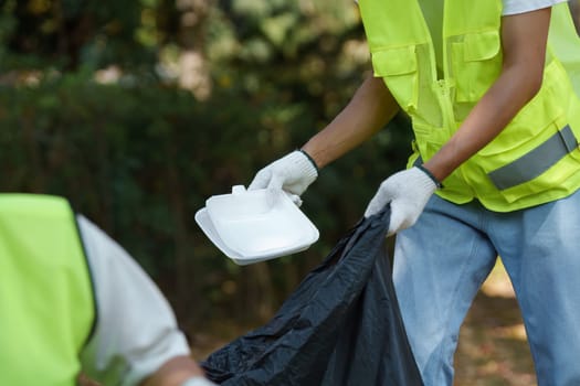 An individual in a safety vest lifts food containers for disposal. This effort promotes recycling and sustainable waste management practices in the community.