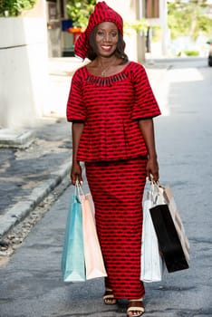 beautiful mature woman in loincloth standing outdoors holding shopping bags while smiling.