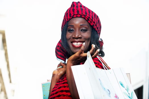 beautiful mature woman in loincloth standing outdoors holding shopping bags and looking at the camera smiling.