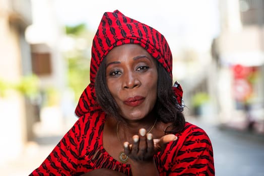 Smiling beautiful young woman in red african outfit makes a flirt on camera. Shopping with love concept