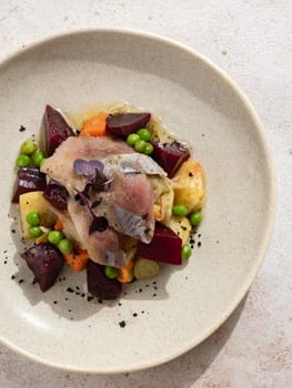 Restaurant dish with fish snack. Salted herring, potatoes, beets, carrots, green peas decorated microgreens. Pickled Herring Fish. Top view or flat lay