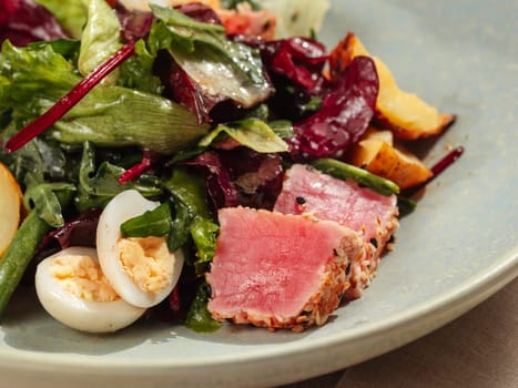 Asian style tuna salad with lettuce, eggs, cherry tomatoes potato and tuna pieces in sesame seeds. Healthy tuna salad. Close up.
