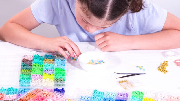Delicate fingers of a young girl navigate through a treasure trove of bright, multicolored beads, each compartment revealing a new hue to choose from.