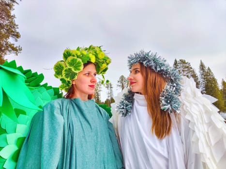 Two girls wearing white and green dresses stand by the lake, capturing the essence of winter and spring in a whimsical role-playing moment.