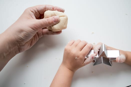 Caucasian child and adult baking together with star cookie cutter.