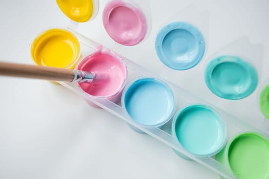 Colorful paint palette with brush. Yellow, pink, light blue, aqua hues for artistic creativity.