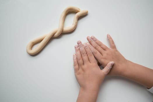 Child forming dough twist with hands in baking activity.