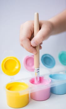 Close up of hand painting with colorful acrylic paints and brush.