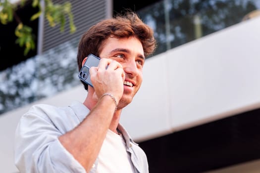 man smiling happy while walking down the street in a good mood talking on cell phone, concept of technology of communication and urban lifestyle, copyspace for text