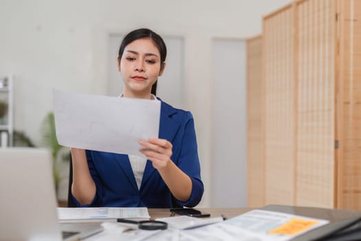 A dedicated businesswoman reviews financial statements while enjoying coffee, emphasizing her role in tax preparation.