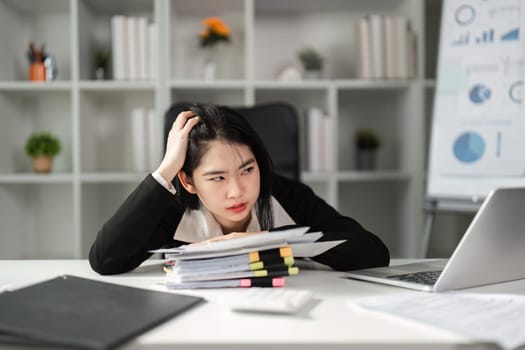 A frustrated businesswoman examines tax paperwork at her desk, facing the pressures of financial management.