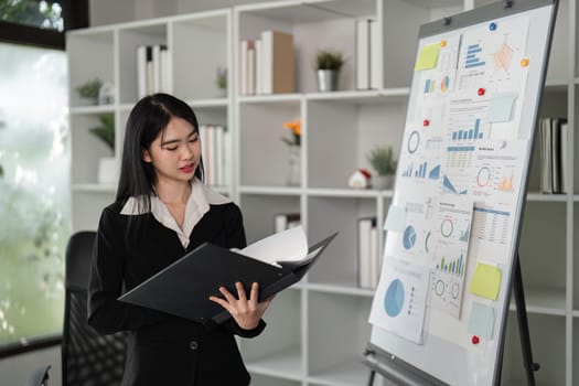 A professional businesswoman examines financial reports and charts, showcasing her analytical skills in a contemporary workspace.