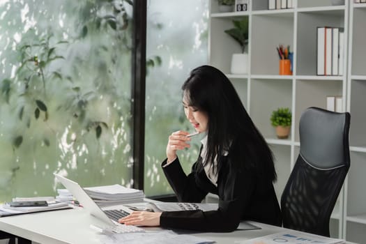A focused accountant multitasks by working on her laptop and discussing financial matters over the phone, showcasing her efficiency and professionalism.