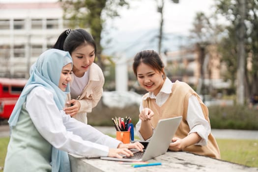 A diverse group of women engaging with a laptop, collaborating joyfully outdoors in a university environment, sharing ideas and learning together.