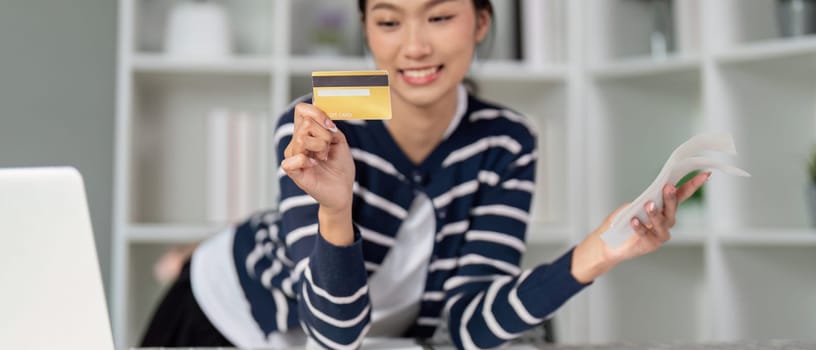 A cheerful woman displays her credit card and a bill, symbolizing financial empowerment.