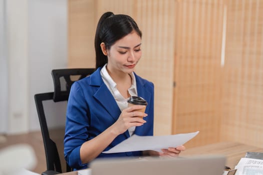 A diligent businesswoman analyzes financial documents and enjoys coffee, highlighting her commitment to tax preparation.