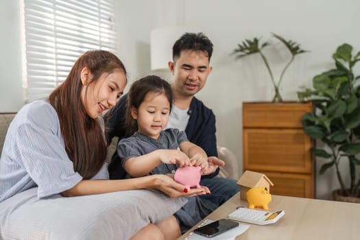 A family sits together, teaching their child about saving money using piggy banks and financial documents.
