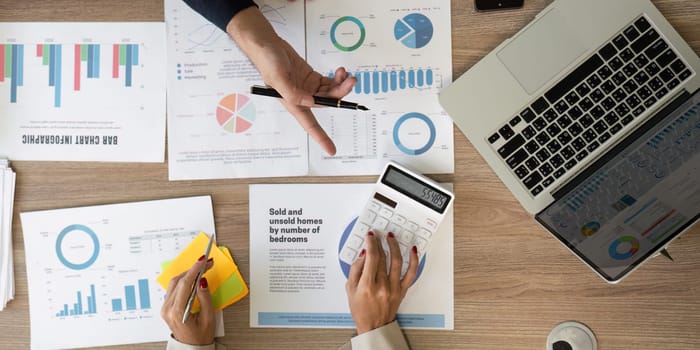 An overhead view of business reports, financial data, and a calculator on a modern workspace table.