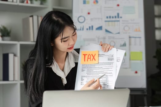 A dedicated accountant examines tax documents, highlighting important details with a sticky note, showcasing her commitment to financial accuracy.