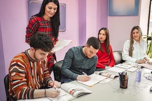 Female teacher explaining subject to her teenage students at language school.