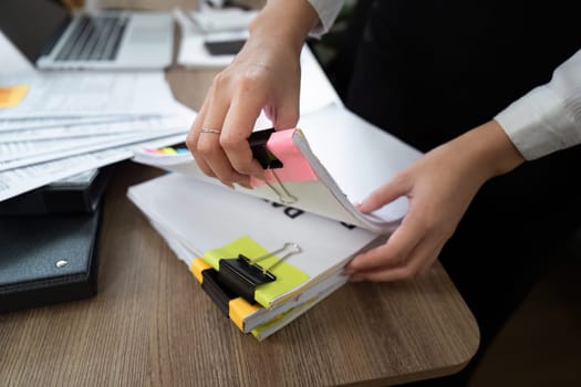 A focused professional organizes documents with binder clips and sticky notes, highlighting attention to detail and organization in business.