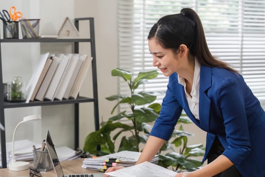 An accountant reviews tax documents and files in a contemporary office setting, showcasing efficiency and professionalism.