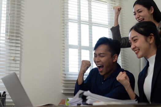 A team celebrates their success after overcoming challenges, showcasing teamwork and joy in a modern office environment.