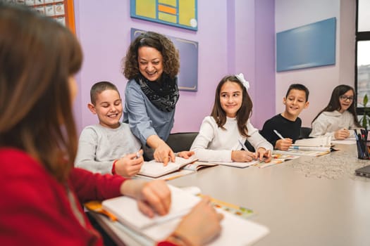 Female teacher helping elementary students at language school class.