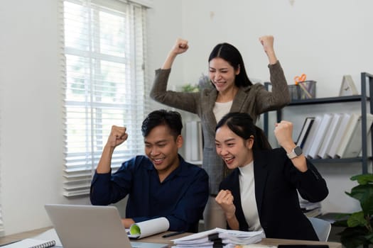 A diverse team joyfully celebrates their success in a bright office, highlighting teamwork and excitement.