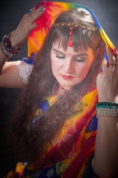 A mature blogger showcases a colorful sari, accentuating traditional elegance while posing softly in an artistic Indian-themed photoshoot.