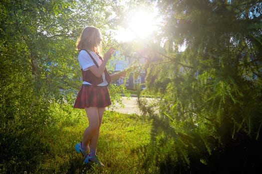A young woman stands in a verdant park, capturing the beauty of nature with her camera as sunlight filters through leaves.
