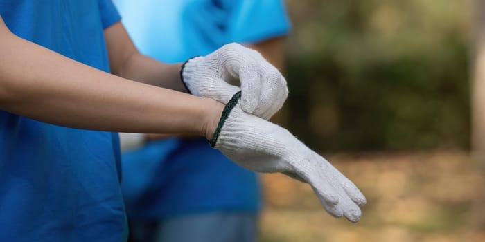 A volunteer puts on gloves, ready to engage in an environmental cleanup activity, promoting sustainability and community involvement.