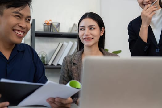A joyful team shares ideas and laughter during a meeting, promoting a positive work atmosphere in a modern office.