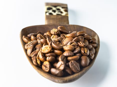 Perspective view of Roasted coffee beans on a rich textured surface in Wooden coffee scoop isolated on the white background. Enjoy your morning coffee for living, use it as your Space for text, Design, Wallpaper and Poster, Selective focus.