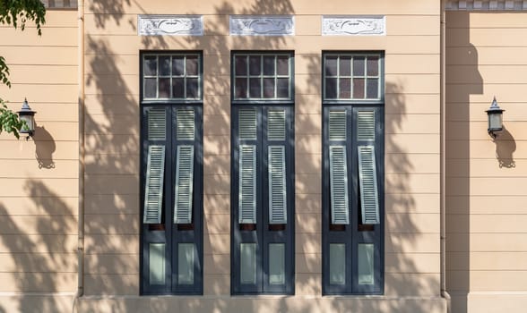 Bangkok, Thailand - Mar 02, 2025 - The Sunlight shines through Multiple green wooden louvered window shutters on cement wall of The Bang Khun Phrom or Bank of Thailand Museum is a magnificent. early 20th century European style palace in neo-Baroque / Rococo style combined German Art Nouveau style, use it as your Wallpaper, Poster and Space for text, Selective focus.
