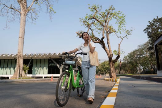 A young woman walks her bicycle and chats on the phone, reflecting a joyful and sustainable lifestyle.