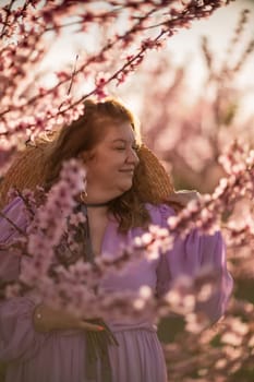 Woman blooming peach orchard. Against the backdrop of a picturesque peach orchard, a woman in a long pink dress and hat enjoys a peaceful walk in the park, surrounded by the beauty of nature