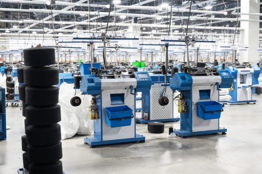 View of automated textile manufacturing machines in a factory, with spools of white thread ready for processing.
