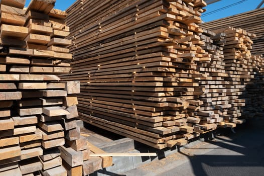 Stacked wooden planks close-up at lumber warehouse. Wood industry concept