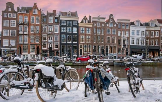 Snowy bikes in Amsterdam in winter in the Netherlands at sunset