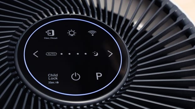 Close up view of Air Purifier with Black Fan. Black Round Electronic Device with Buttons and Bright Lights on White Background.