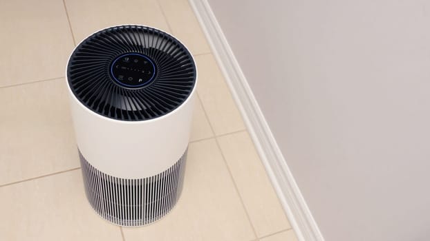 Sleek Modern Tall Air Purifier with Black Fan on Beige Tile Floor in Stylish Room.