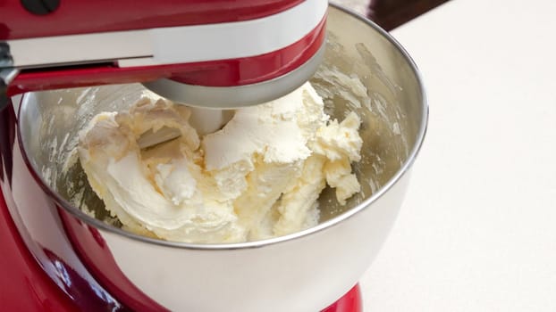 Close-Up of a Red Stand Mixer with a Silver Bowl Filled with Fluffy Whipped Cream and Baking Tools.