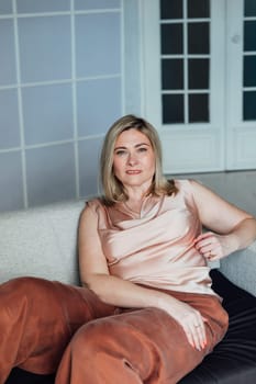 Woman in home clothes sitting on sofa in room interior