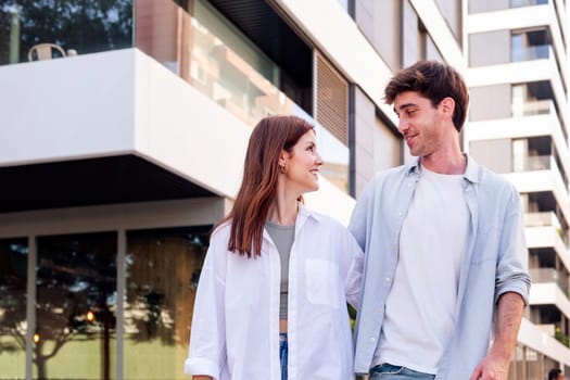 young man and woman smiling happy to each other while talking in a romantic walk down street, concept of couple and urban lifestyle