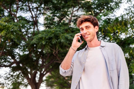 man smiling happy while walking in a good mood talking on mobile phone, concept of technology of communication and urban lifestyle, copyspace for text