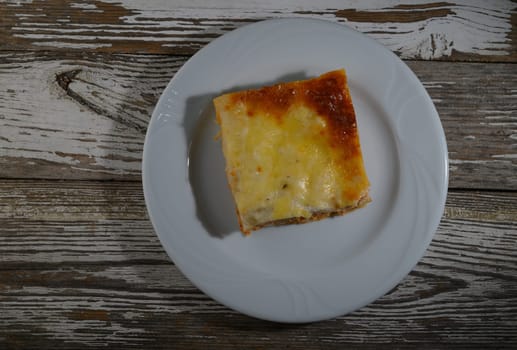 A delectable square of baked casserole sits on a white plate, inviting for a warm meal at dinner time.